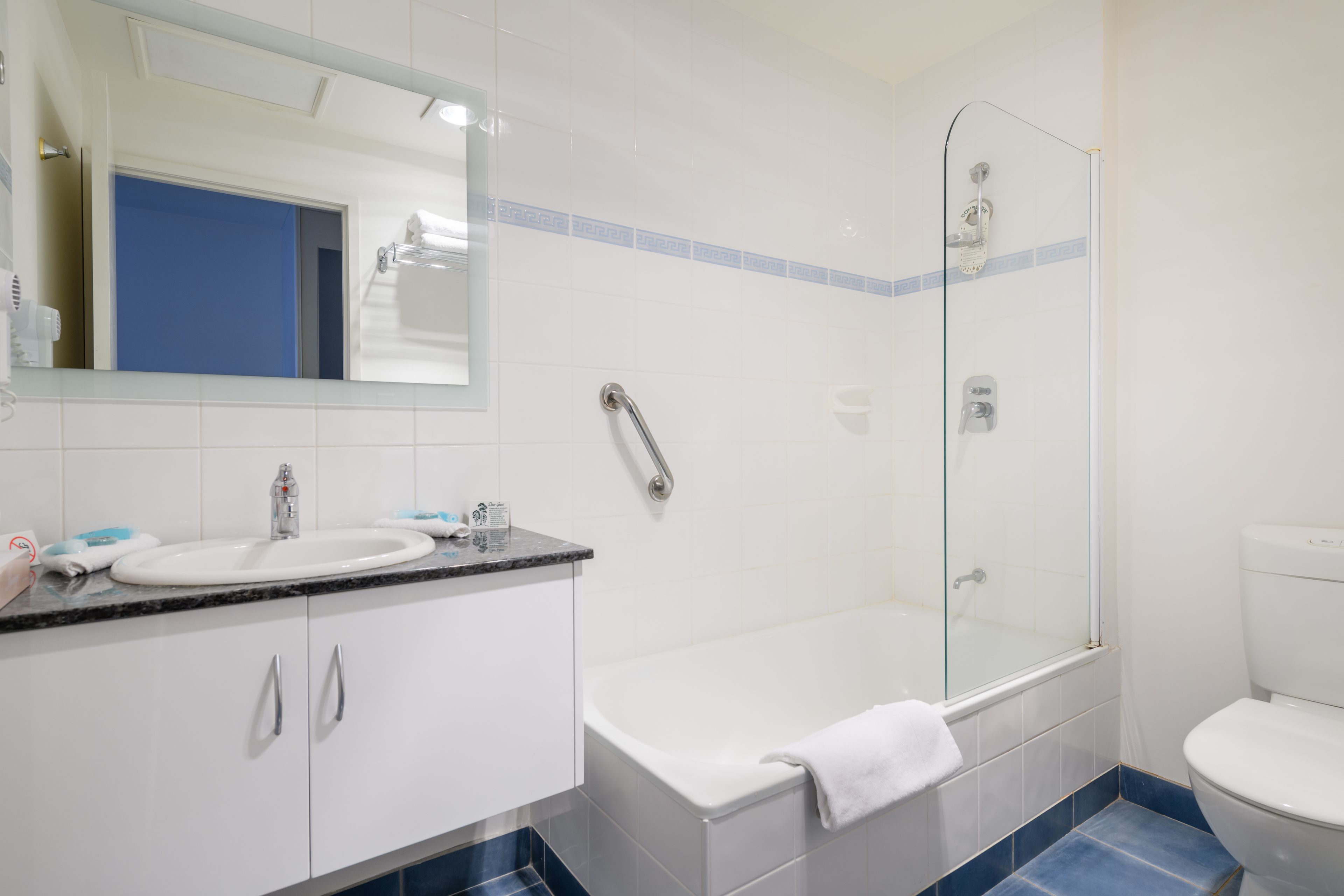 A bathroom with a white sink, a glass shower enclosure, and a white toilet.
