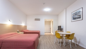 A hotel room with two beds, a dining table with yellow chairs, a TV, and a framed picture on the wall. - Mayfair Plaza Motel (Sandy Bay)