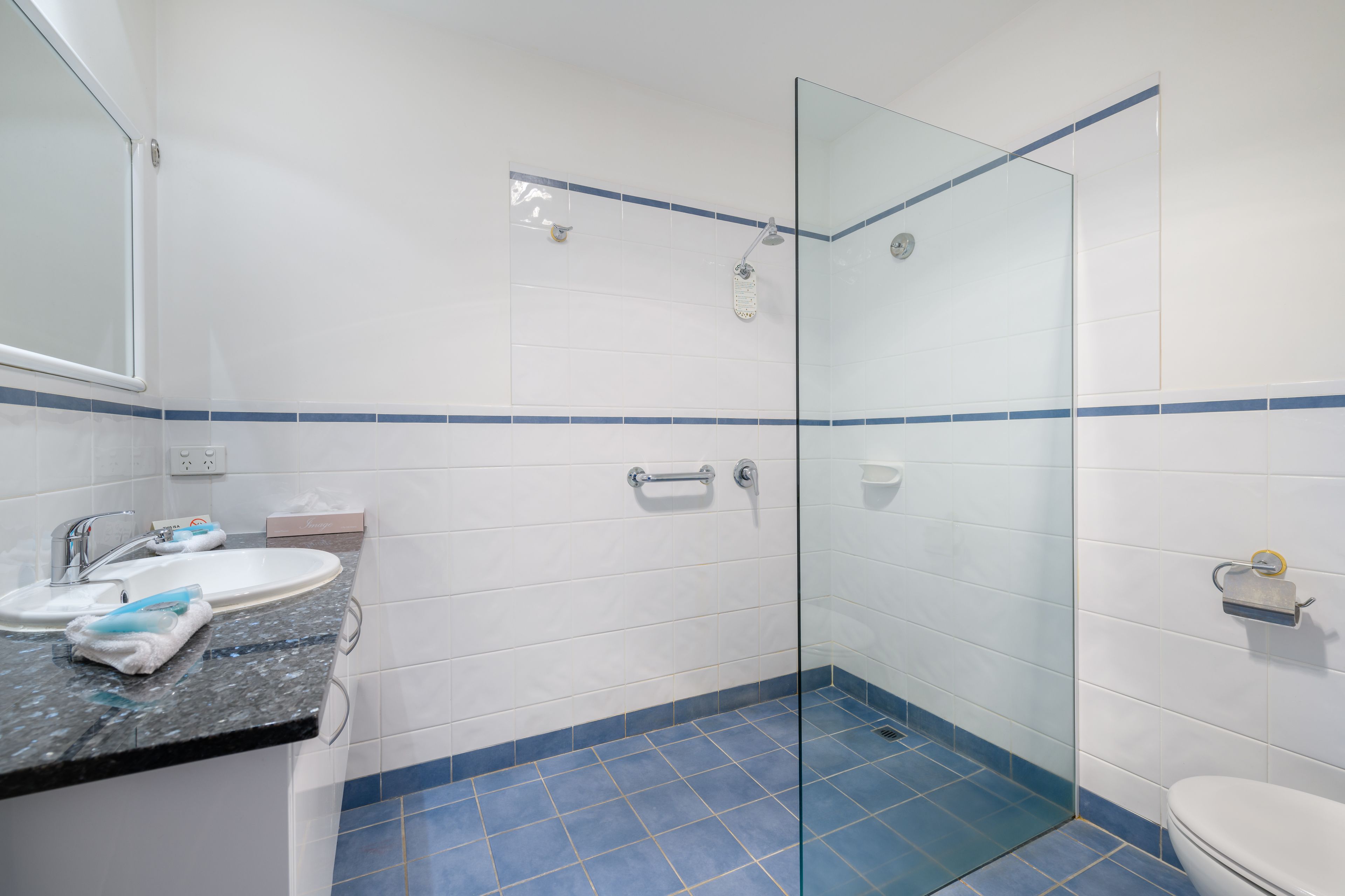 A bathroom with a glass shower enclosure, a sink with a mirror, and a toilet.