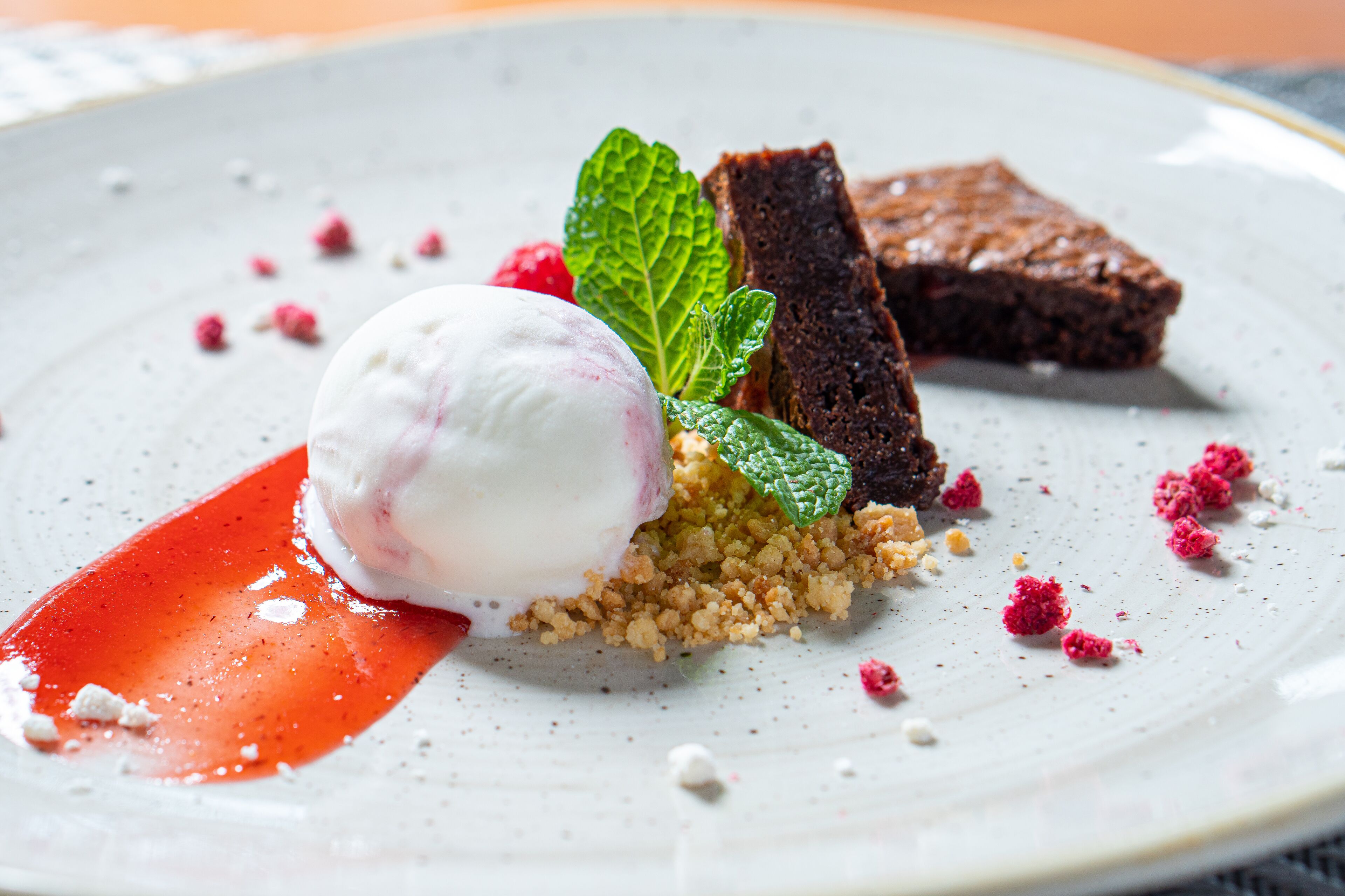 Un plato de postre con una bola de helado, un trozo de pastel y algunas bayas.