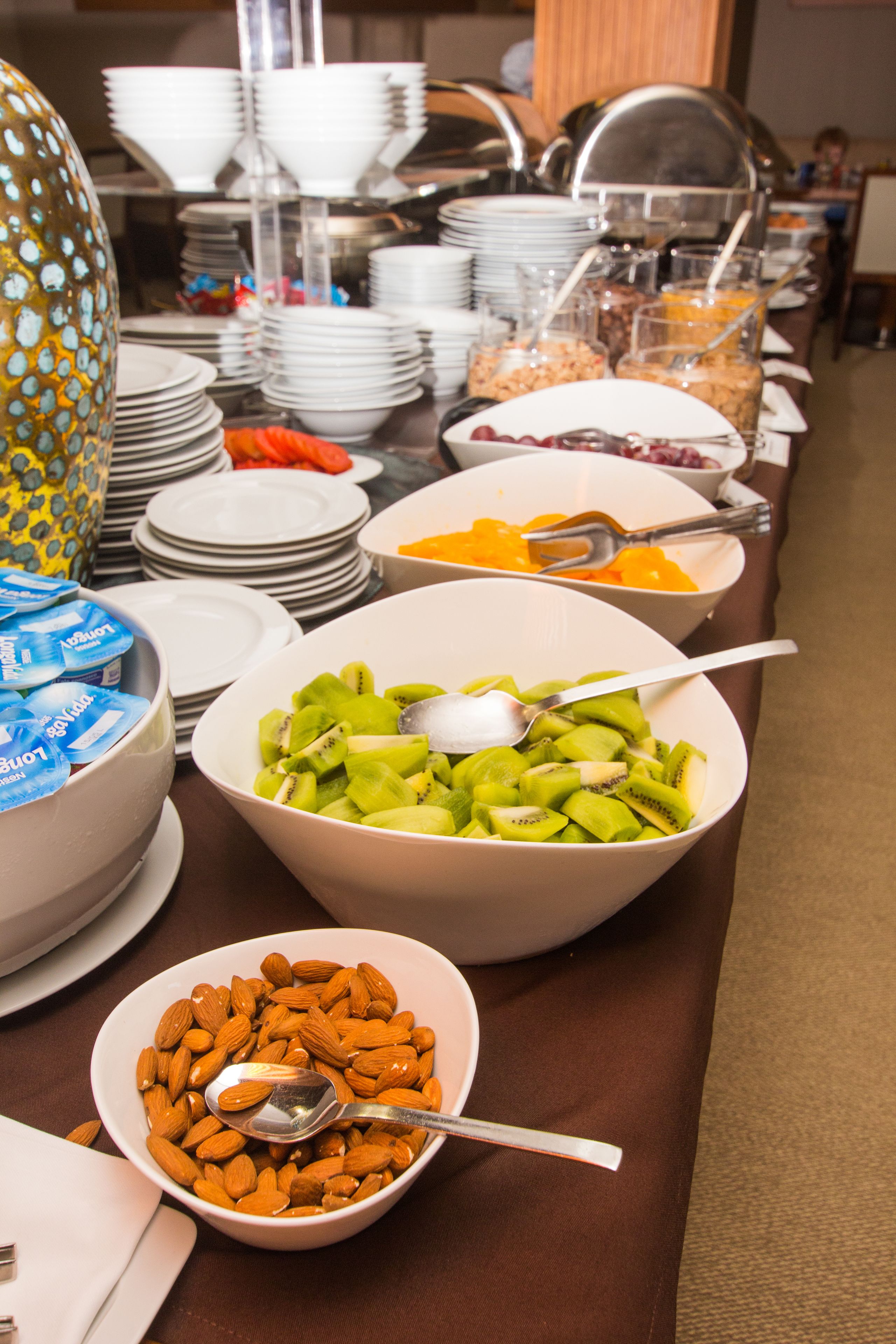 Une table de buffet proposant une variété d’aliments, notamment des fruits, des noix et des céréales.