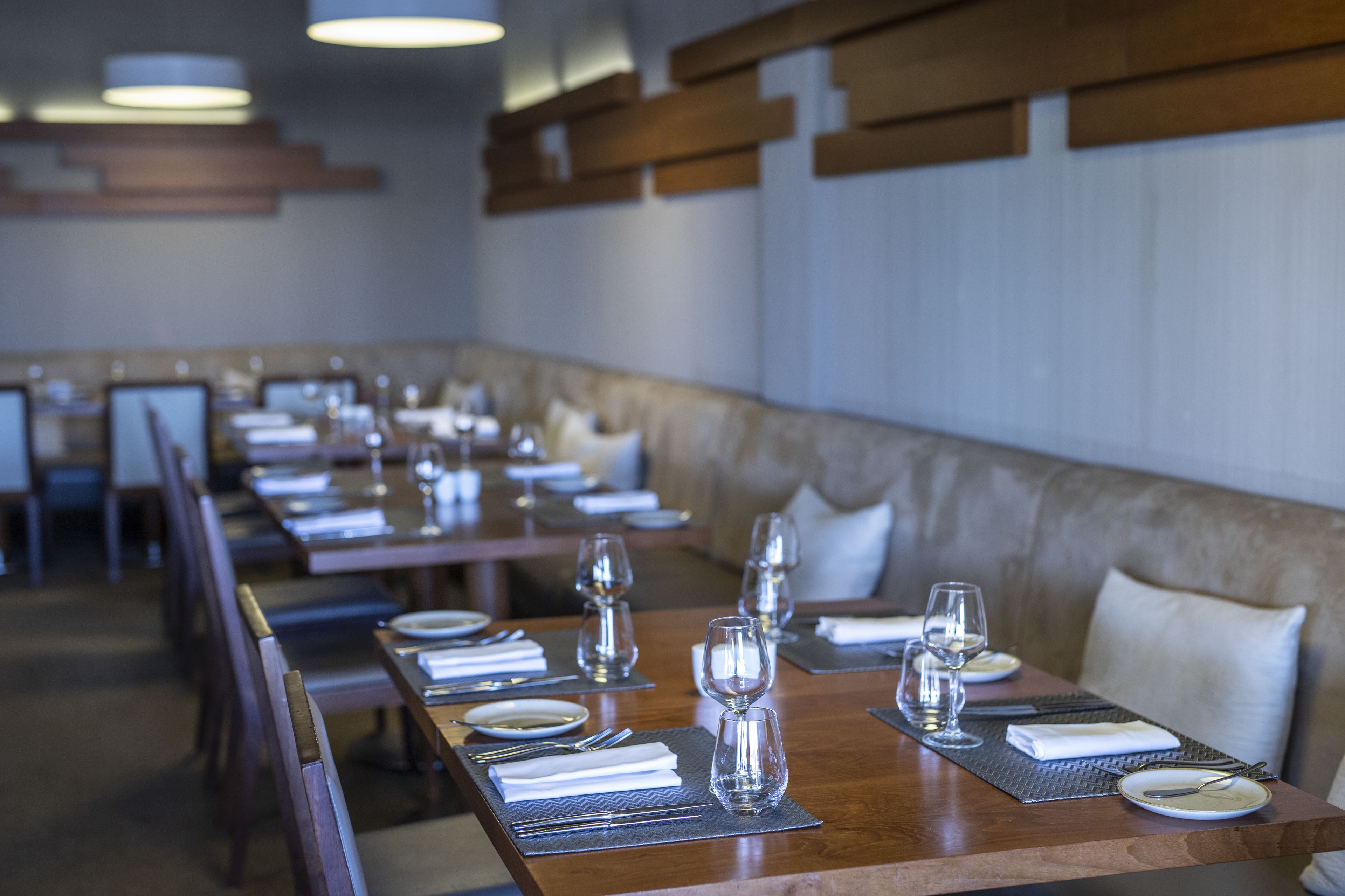 A dining area with long tables set for a meal, including plates, cutlery, and glasses.