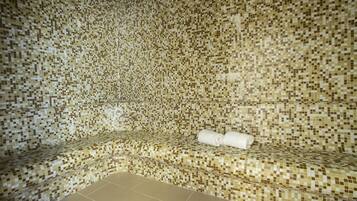 Relax in a serene space with a mosaic tile wall and floor, featuring a comfortable bench and a bathtub.