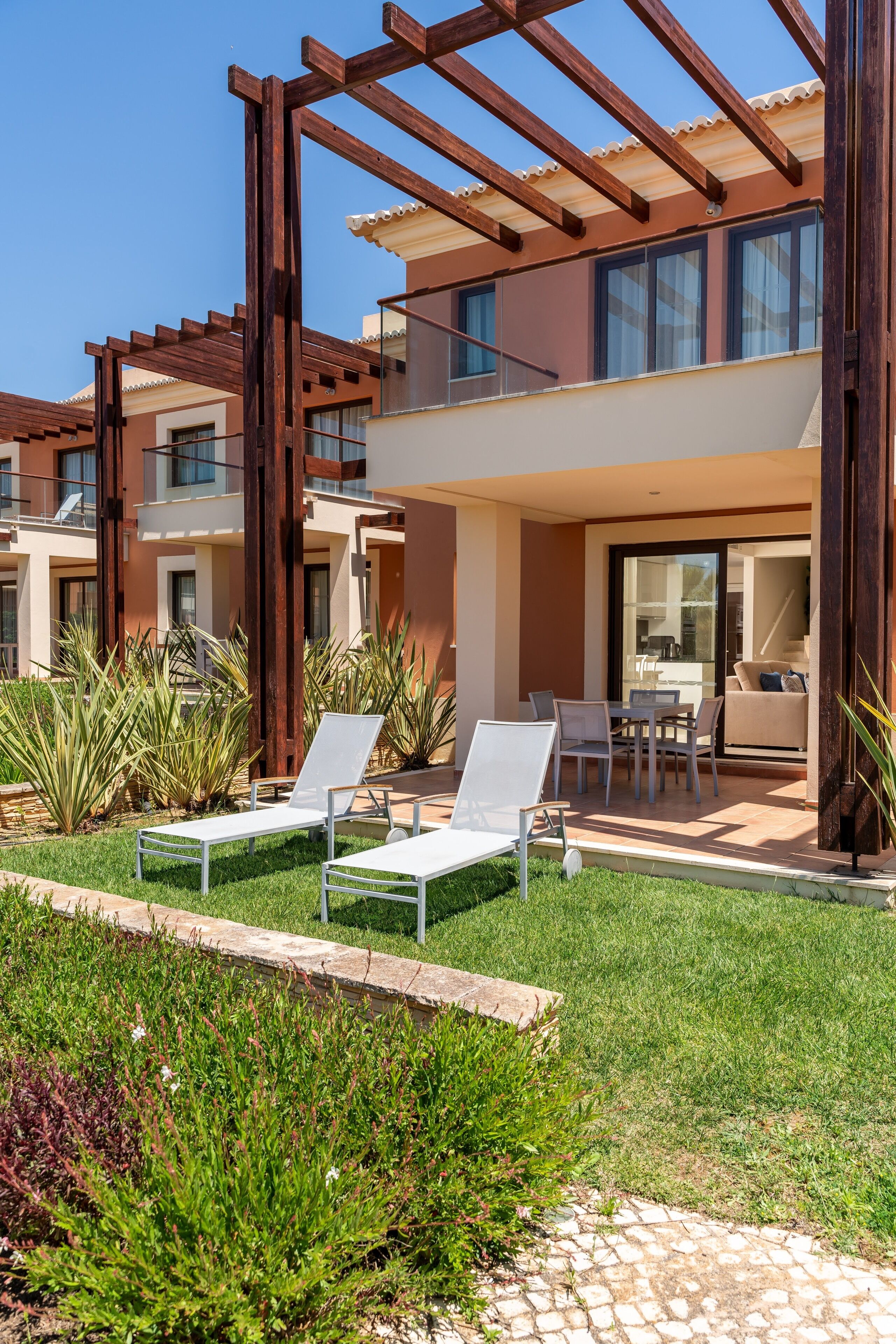 Un moderno complejo de apartamentos con zonas de estar al aire libre, un patio cubierto y un jardín bien cuidado.
