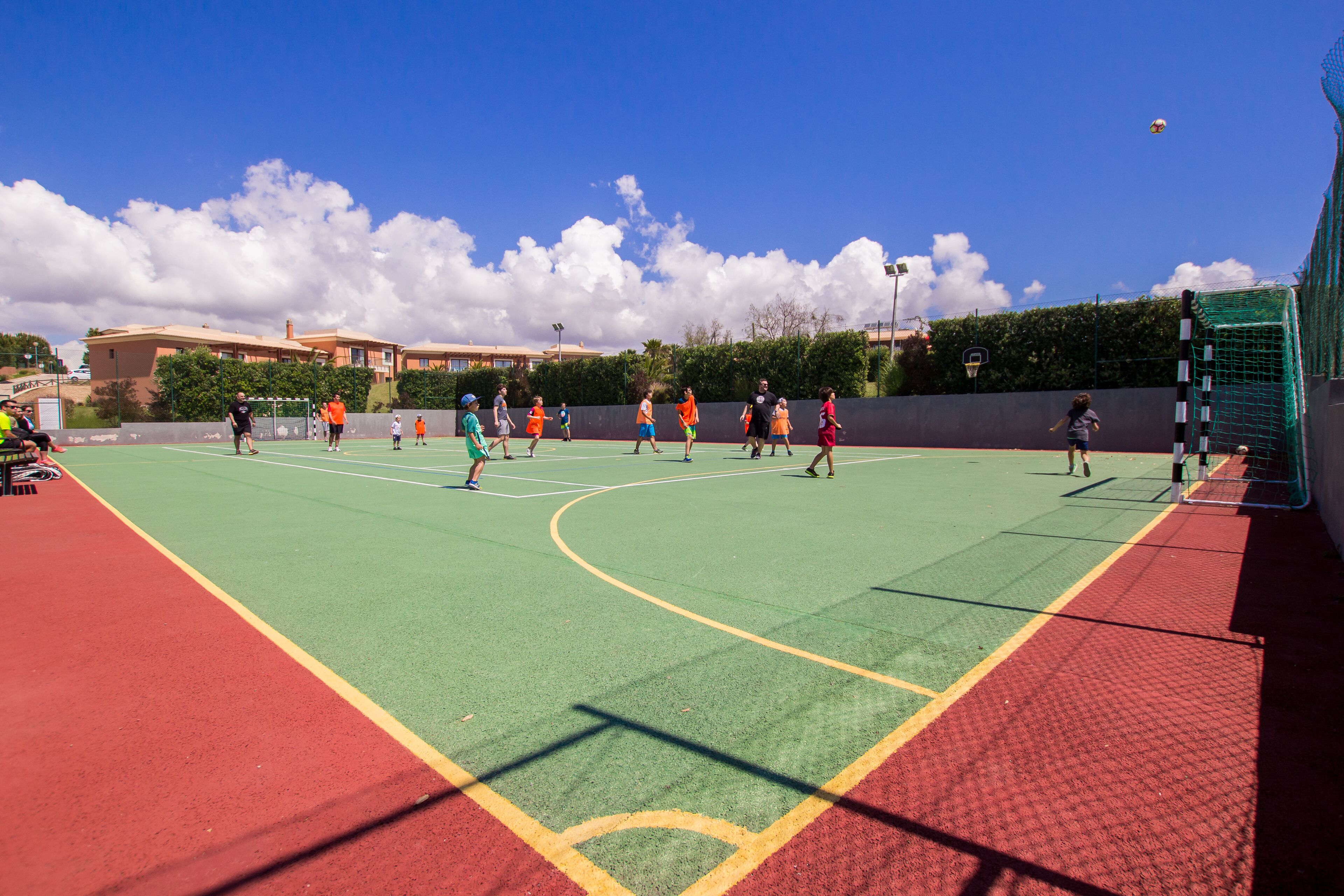 A sports court with multiple players, a basketball hoop, and a net.