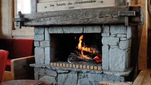 Un interior rústico con chimenea de piedra, muebles de madera y un cuadro colgado en la pared.
