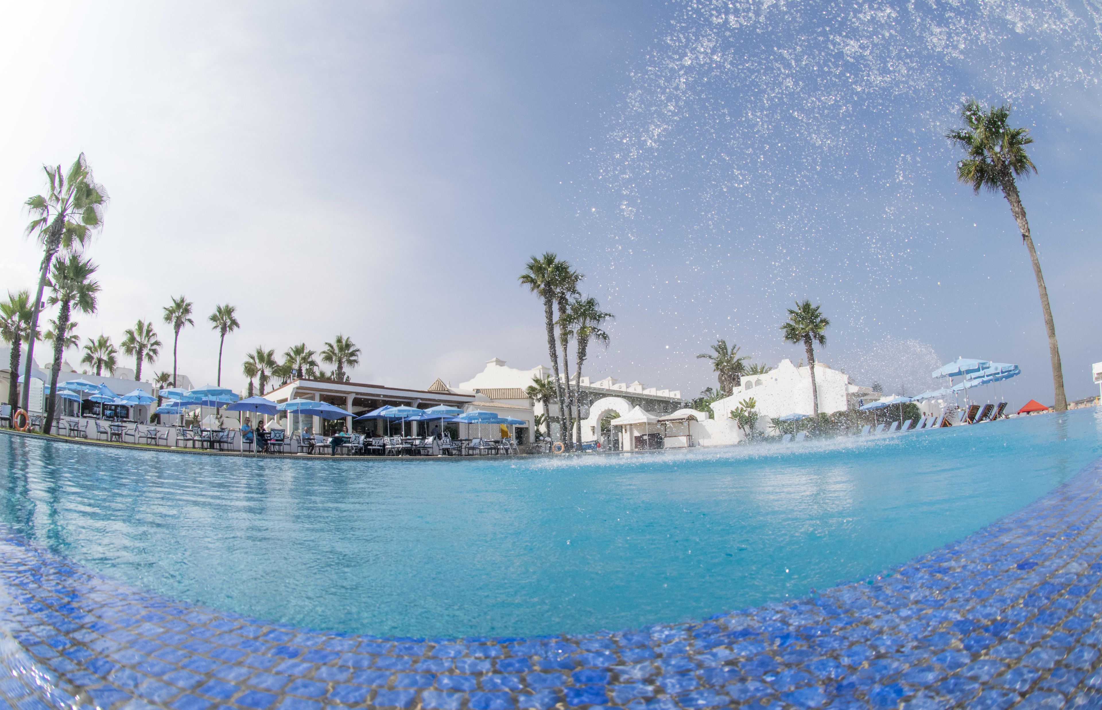 Una piscina techada, una piscina al aire libre, sombrillas