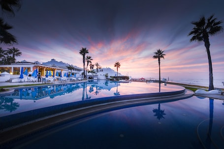 Una piscina techada, una piscina al aire libre, sombrillas