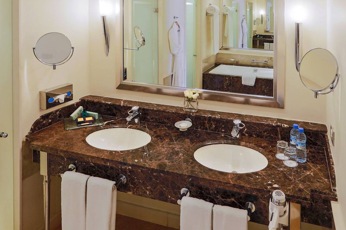 A bathroom with two sinks, a large mirror, and a towel rack.