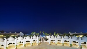 A night view of a hotel with white domed structures and a central staircase leading to a pool area. - L'amphitrite Palace Resort & Spa (Skhirat)