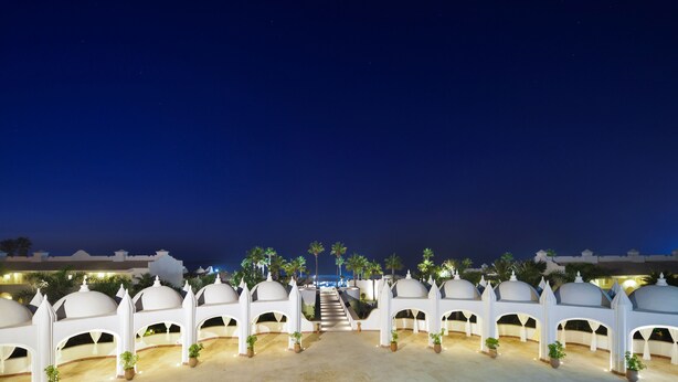 A night view of a hotel with white domed structures and a central staircase leading to a pool area. - L'amphitrite Palace Resort & Spa (Skhirat)
