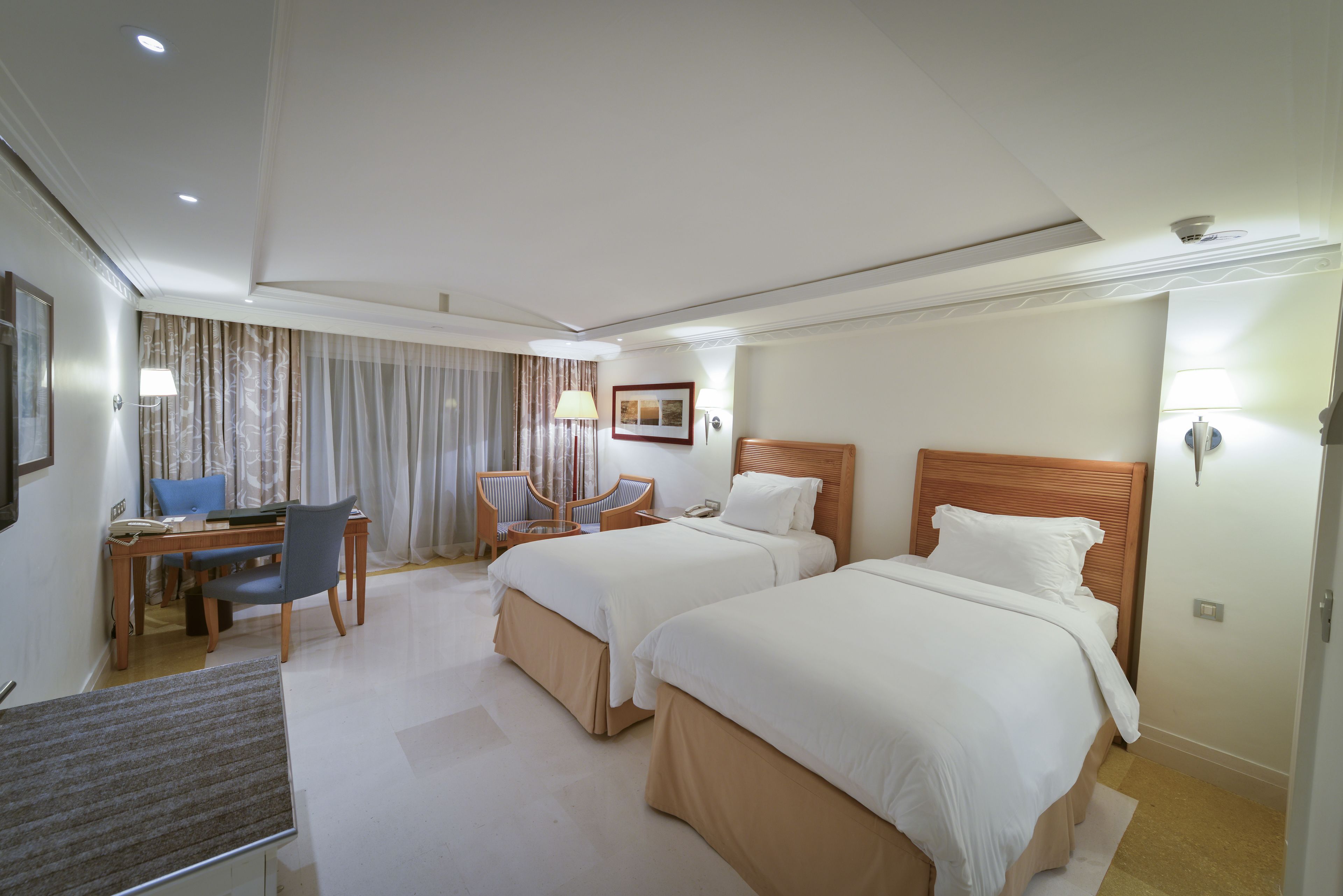 Een hotelkamer met twee bedden, een bureau en een stoel.