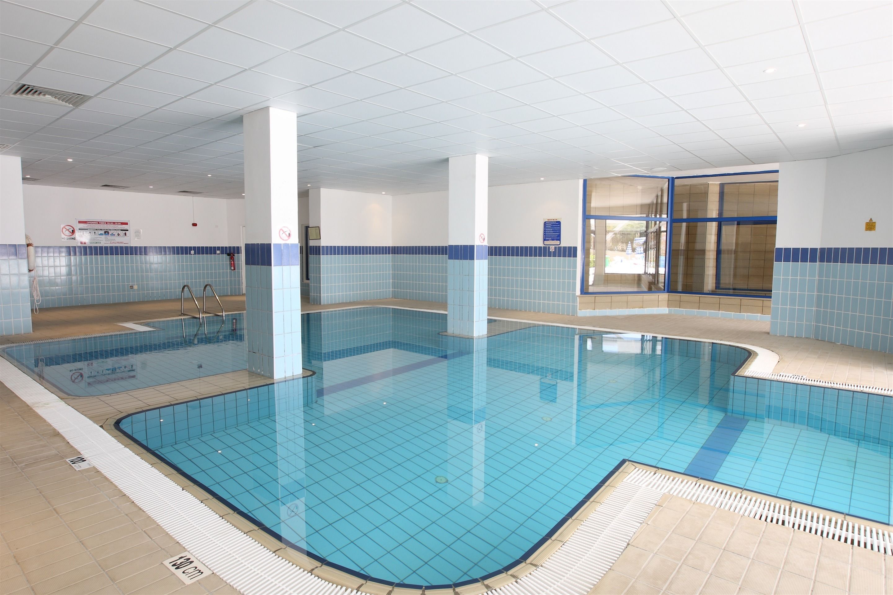 A large indoor swimming pool with tiled walls and a tiled floor.
