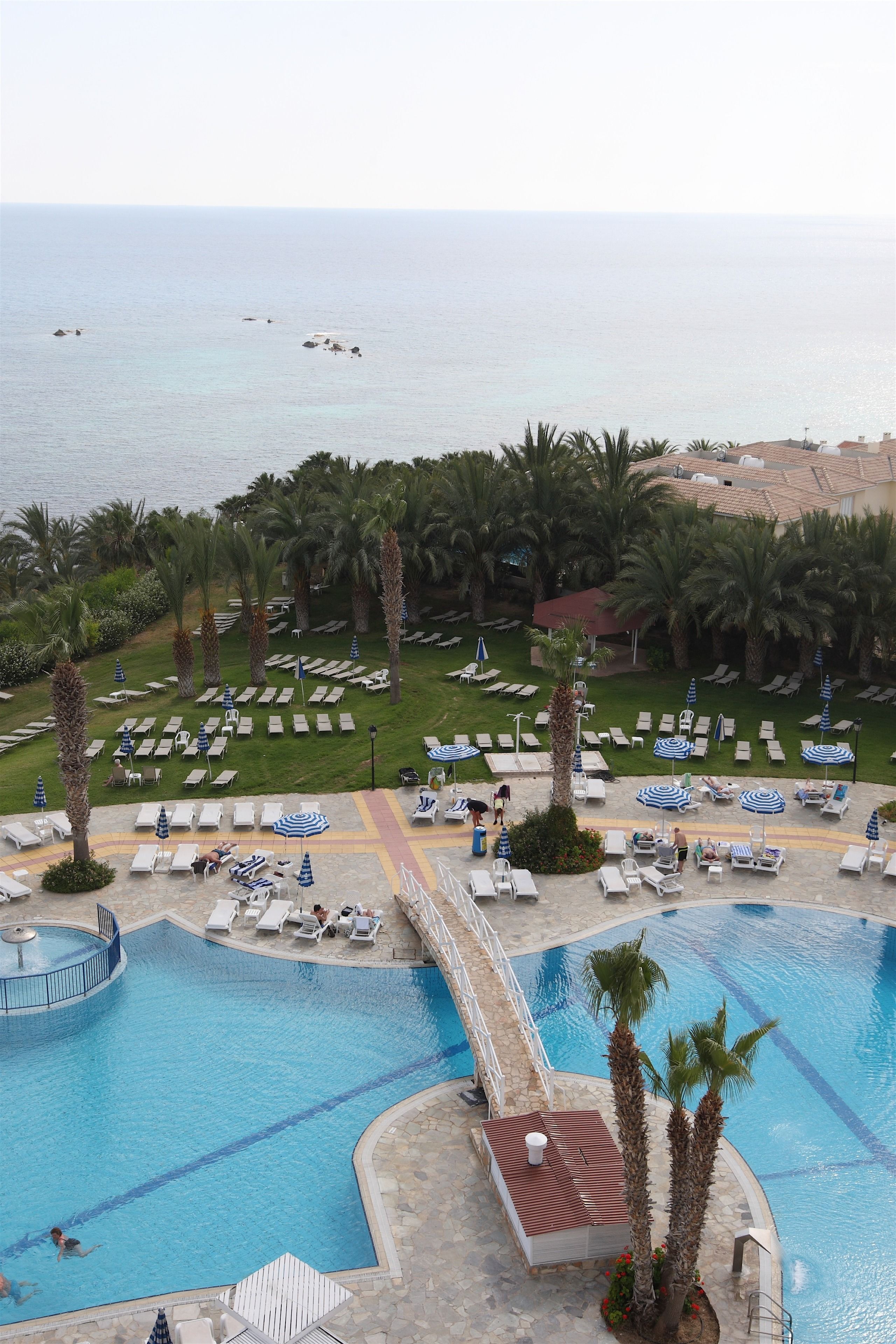 Un complexe hôtelier doté de plusieurs piscines, de chaises longues et de palmiers.
