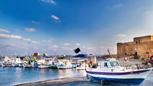 Un port où des bateaux sont amarrés, avec un bâtiment historique en arrière-plan.