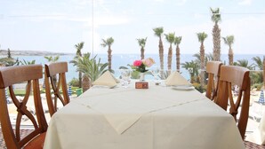 Une table dressée pour deux personnes, avec vue sur la mer et les palmiers.