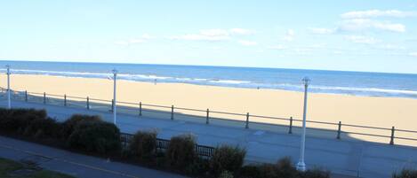 Blick auf einen Strand mit Gehweg, Bänken und Straßenlaternen.