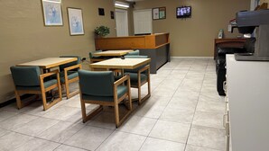 A restaurant with wooden tables and chairs, a counter, and a television on the wall. - Americas Best Value Inn Wendover (Wendover)