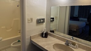 A bathroom with a bathtub, toilet, sink, and a large mirror. - Americas Best Value Inn Wendover (Wendover)