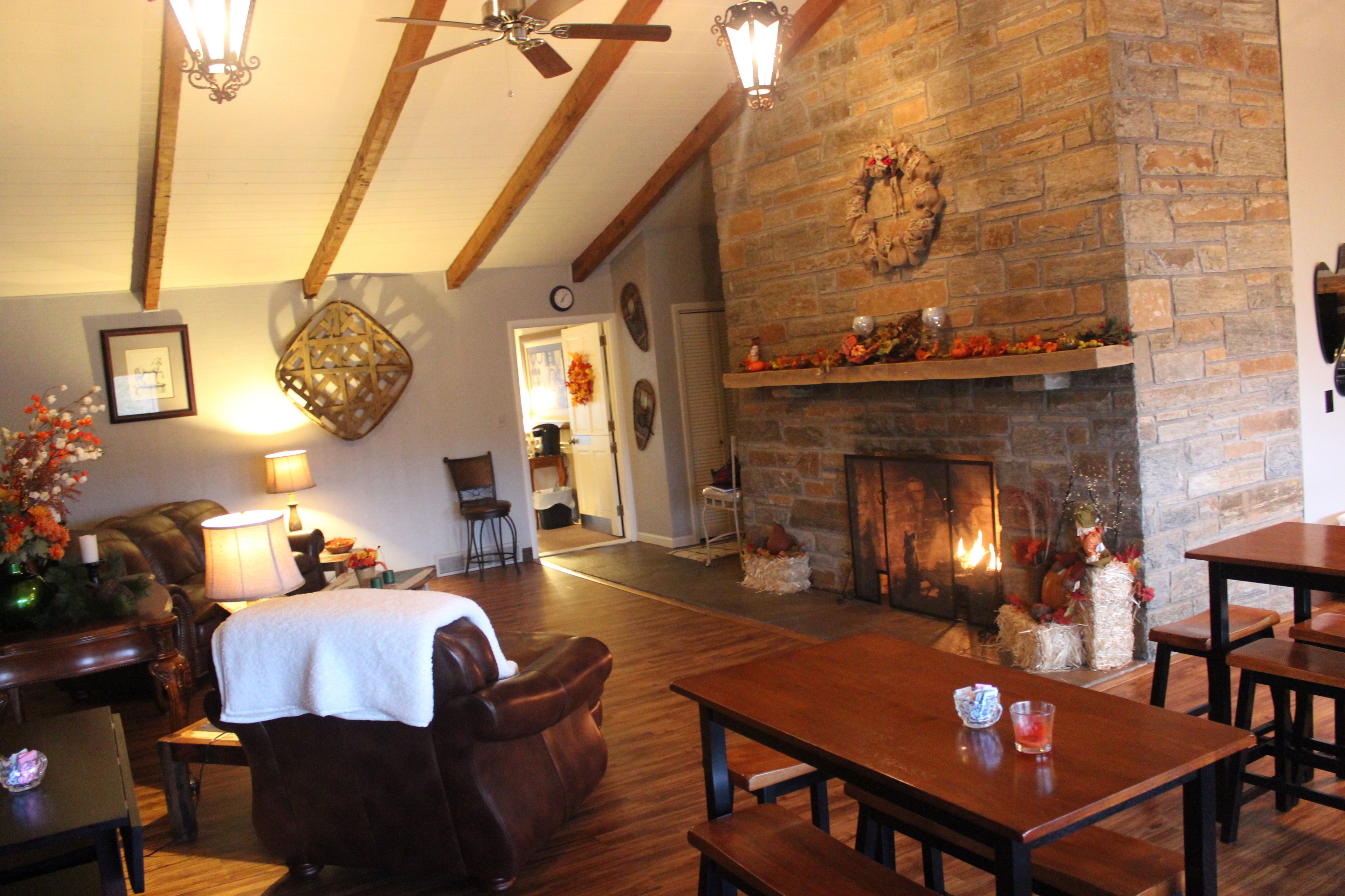A cozy living room with a fireplace, wooden furniture, and a ceiling fan.