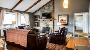 A cozy living room with a stone fireplace, leather furniture, and a wooden ceiling. - Cliff Dwellers Inn (Blowing Rock)