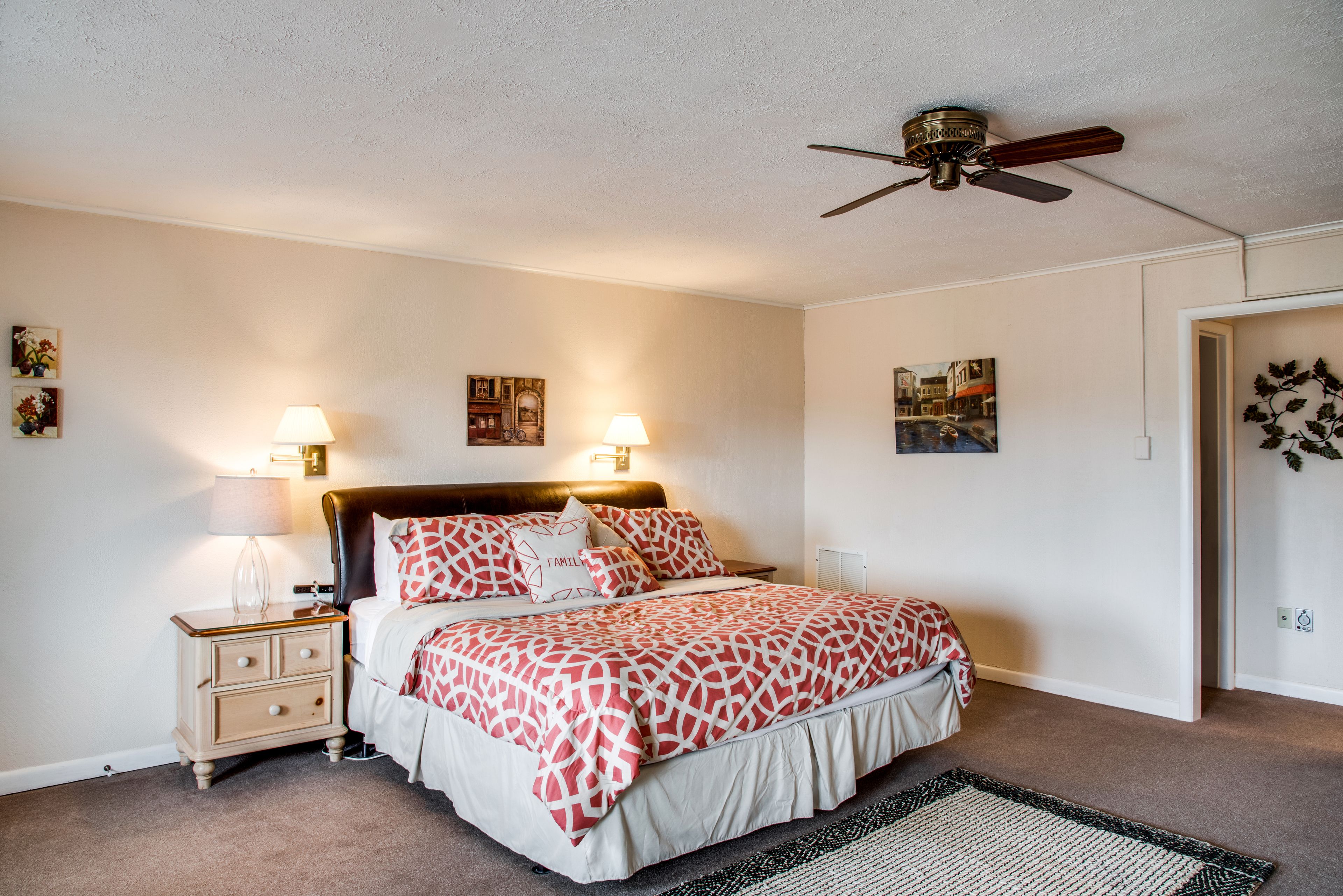 A bedroom with a bed, nightstands, lamps, and ceiling fan.