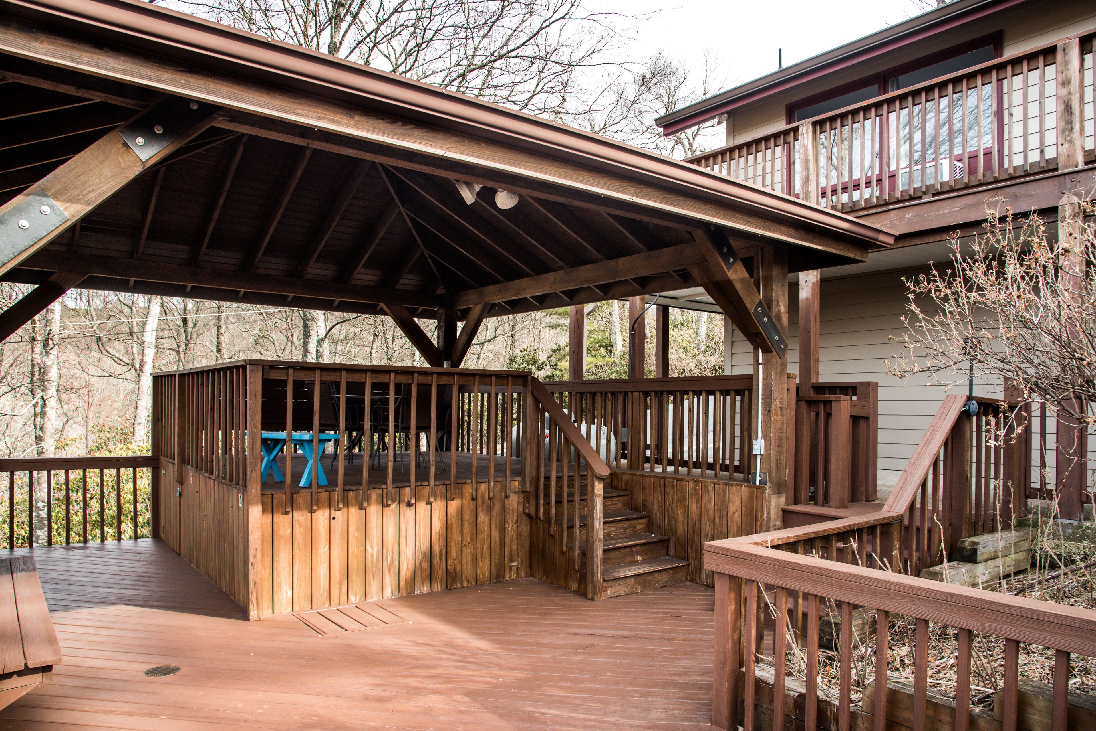 A wooden deck with a covered seating area and a staircase leading to an upper level.