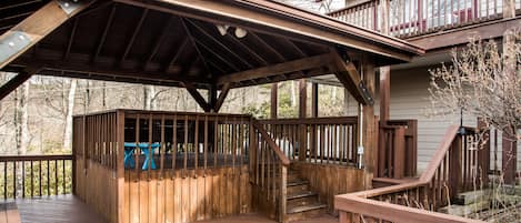 A wooden deck with a covered seating area and a staircase leading to an upper level.