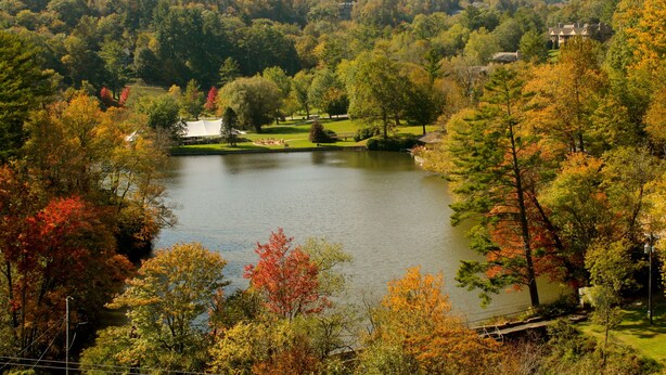 A lake surrounded by autumn foliage, a golf course, and a house on a hill. - Cliff Dwellers Inn (Blowing Rock)