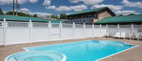A rectangular swimming pool with a diving board and a white fence.
