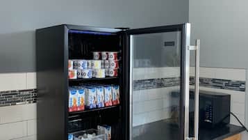 Una cocina con un refrigerador lleno de bebidas y un microondas.