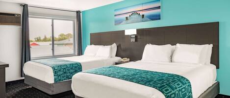 A hotel room with two beds, a large window, and a painting on the wall.