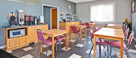 Un comedor con mesas y sillas de madera, una estación de café y una encimera de cocina.