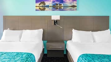 A hotel room with two beds, a nightstand, a wall-mounted lamp, and a painting above the bed.