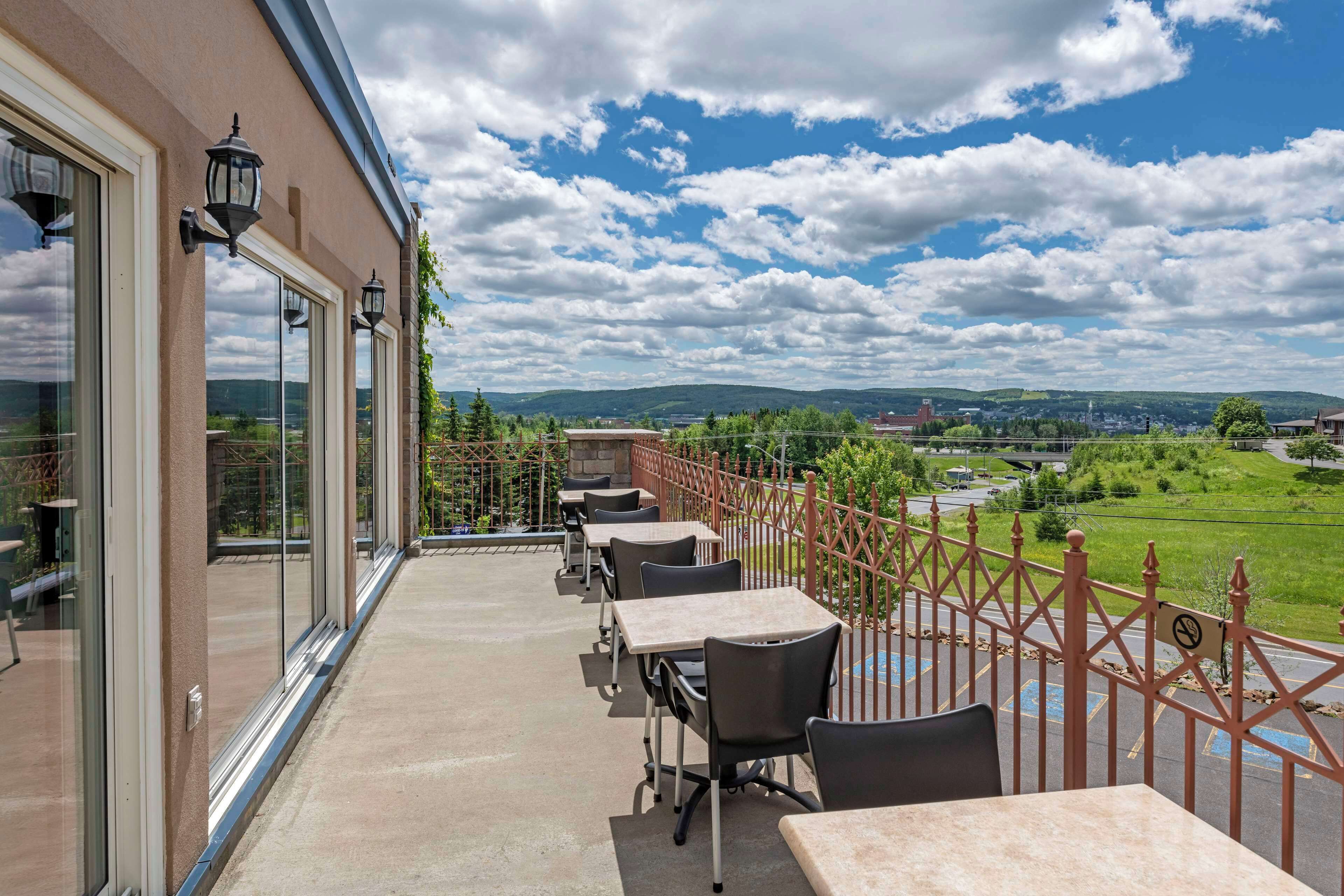 Un balcon avec coin salon extérieur, de grandes fenêtres et une vue sur la campagne.
