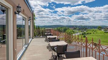 Un balcon avec coin salon extérieur, de grandes fenêtres et une vue sur la campagne.