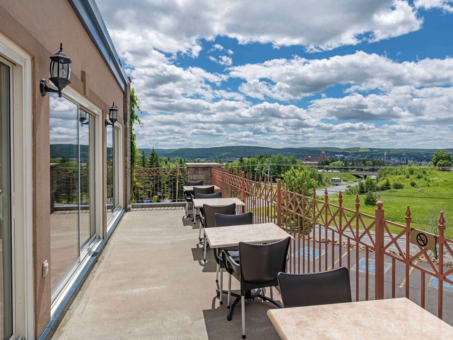 Un balcon avec coin salon extérieur, de grandes fenêtres et une vue sur la campagne.
