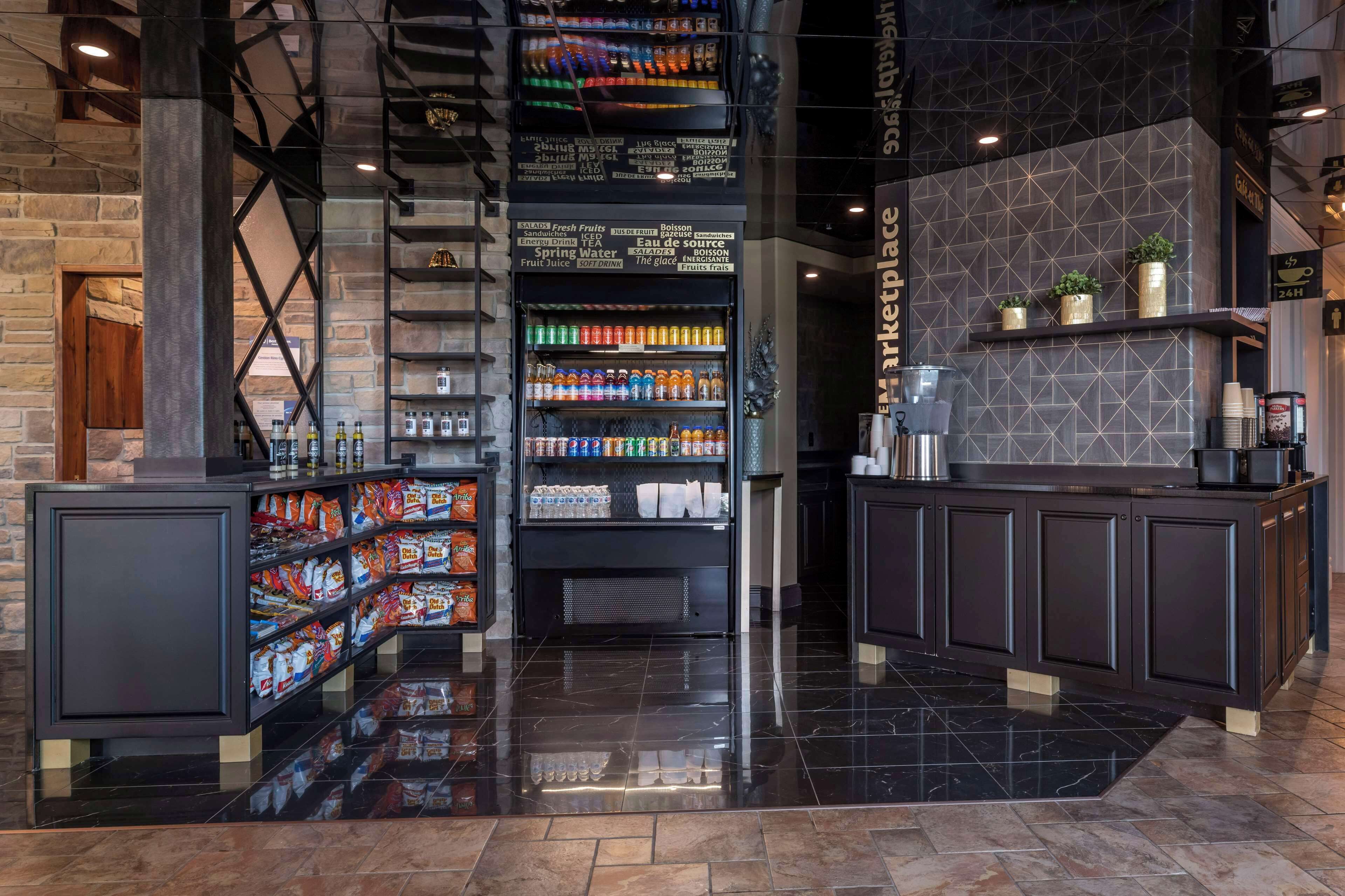 Un lobby moderno con una escalera central, un bar de aperitivos y una estación de café.