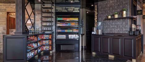 Un lobby moderno con una escalera central, un bar de aperitivos y una estación de café.