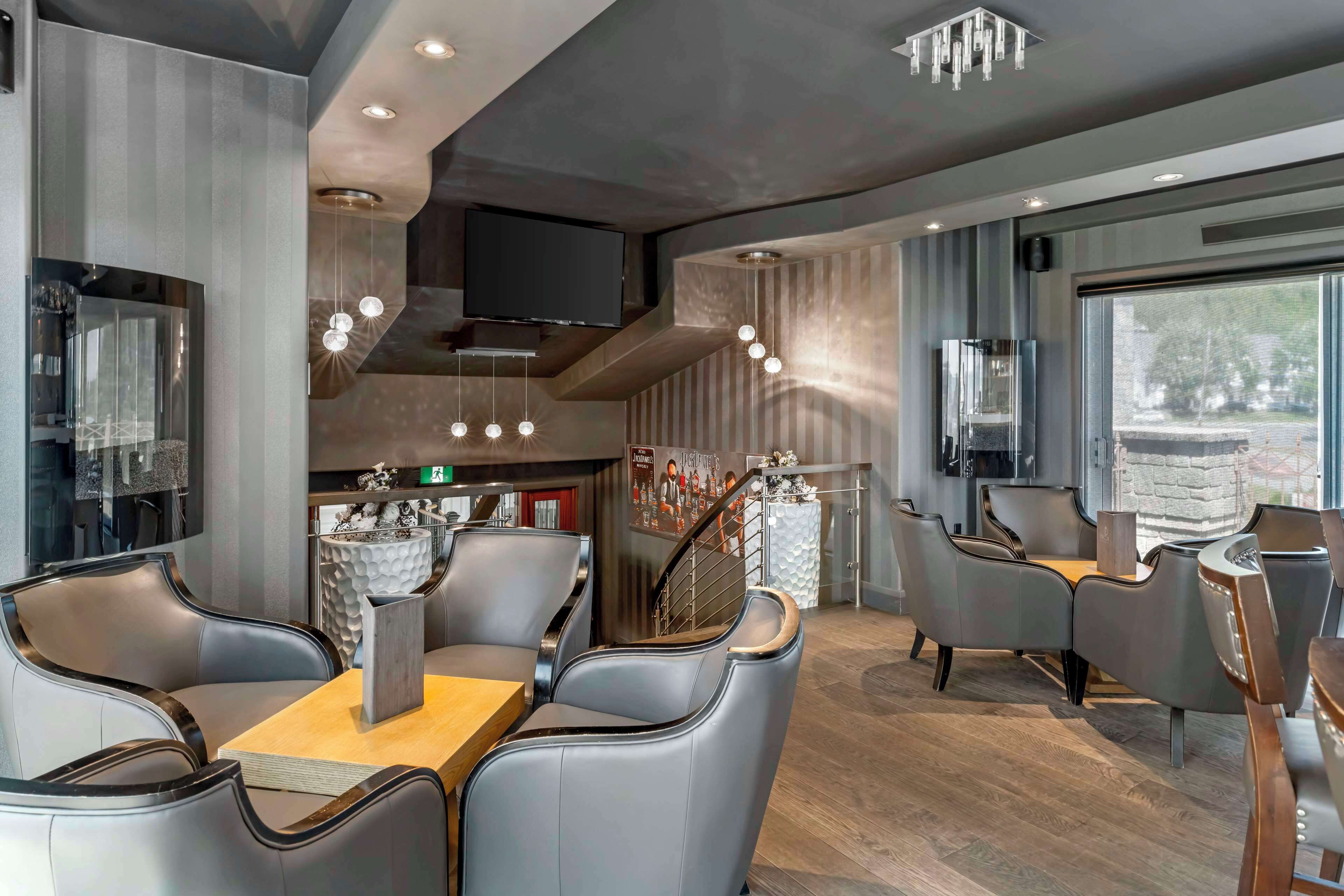 Un restaurant moderne doté de sièges en cuir, d’un téléviseur à écran plat et d’une grande fenêtre offrant une vue panoramique.