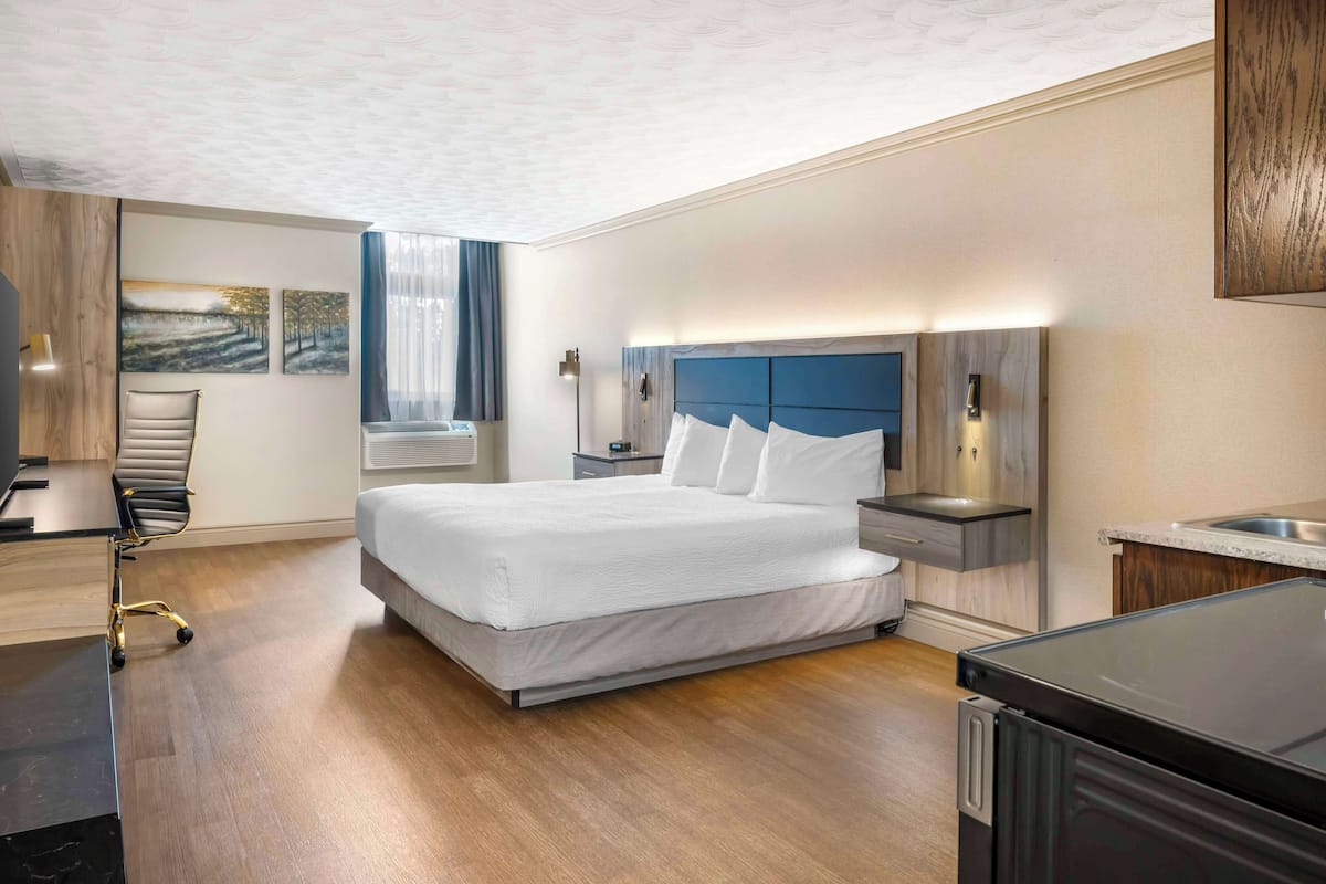 Une chambre d’hôtel moderne dotée d’un grand lit, de tables de chevet, d’un bureau et d’un coin cuisine intégré.