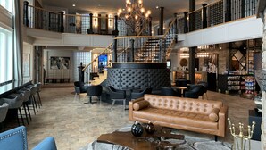 A spacious lobby with a high ceiling, a grand staircase, and a bar area. - Best Western Plus Edmundston Hotel (Edmundston)
