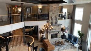 A spacious living area with a fireplace, a chandelier, and a high ceiling with exposed beams. - Best Western Plus Edmundston Hotel (Edmundston)