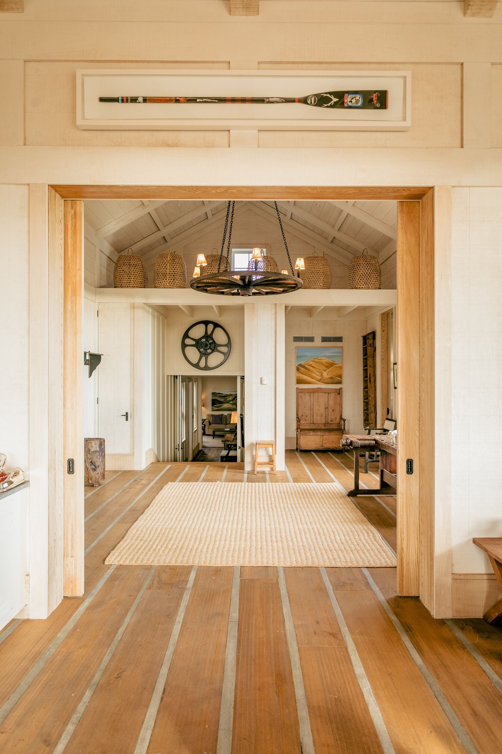 A spacious hallway with wooden flooring, a large circular wall decoration, and a hanging light fixture.