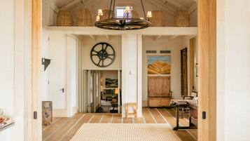 A spacious hallway with wooden flooring, a large circular wall decoration, and a hanging light fixture.