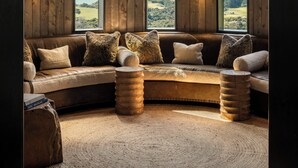 Una habitación acogedora con un sofá curvo, ventanas amplias y vistas del paisaje.