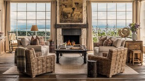 Un salón amplio con chimenea, ventanas grandes y vistas al paisaje.