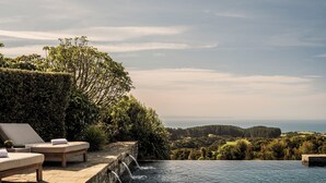 A infinity pool with lounge chairs and a view of the landscape. - Rosewood Cape Kidnappers (Clifton)