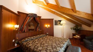 Une chambre avec un plafond en bois, un lit recouvert d’une couvre-lit à motifs floraux, une table de chevet avec une lampe et une chaise.