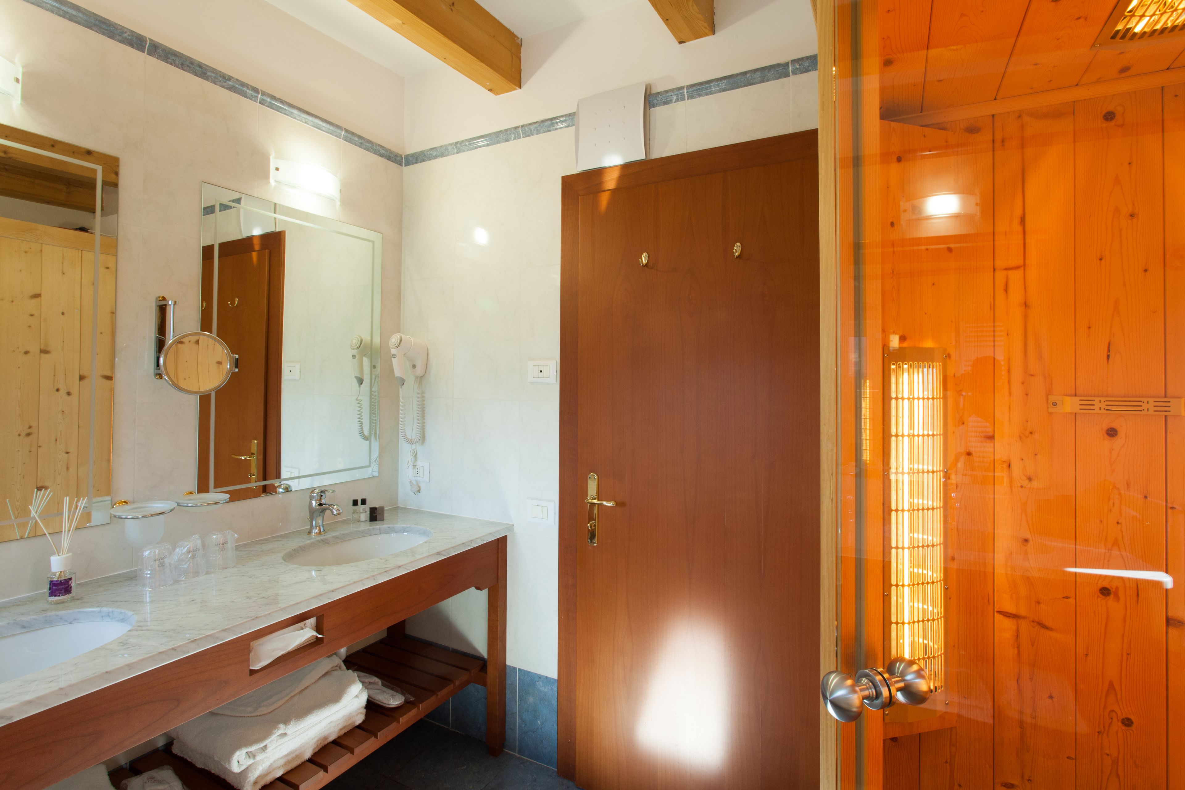 Een badkamer met twee wastafels, een spiegel en een houten deur.